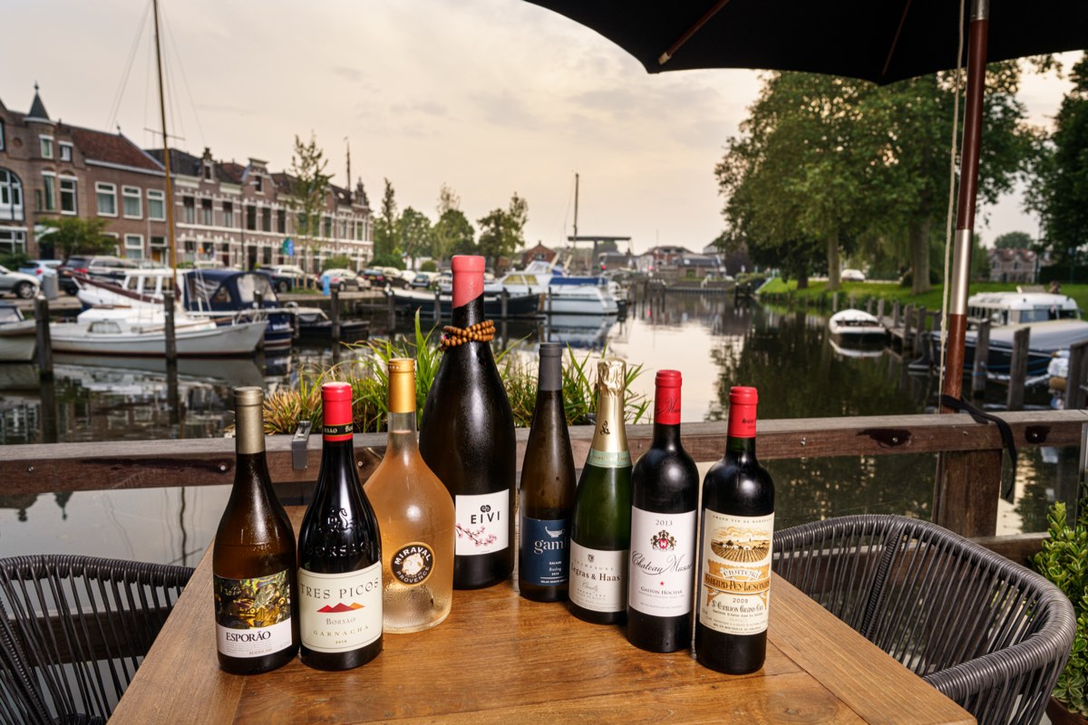 Wijnflessen op tafel met uitzicht op de haven van Woerden